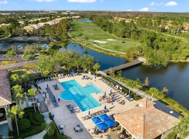 Aerial view of a pool area, a nearby body of water, and a local golf course