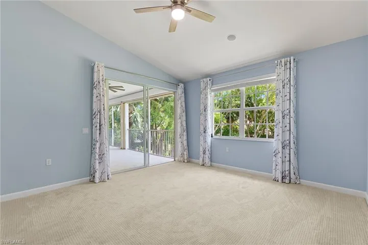 Carpeted empty room featuring ceiling fan, vaulted ceiling, and baseboards