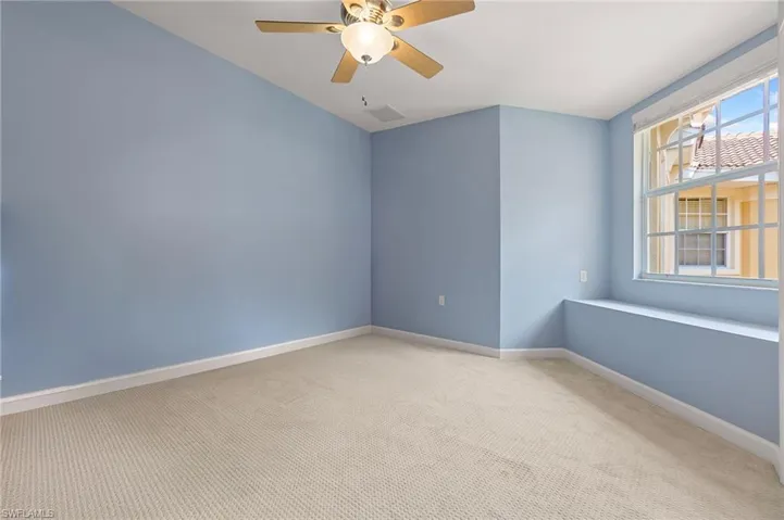 Spare room with light colored carpet, baseboards, and ceiling fan