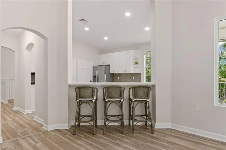 Kitchen featuring stainless steel fridge, white cabinets, open shelves, light wood-style floors, and recessed lighting