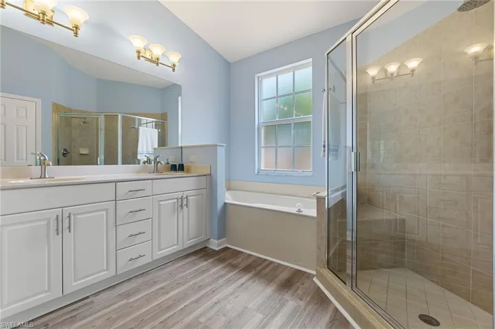 Bathroom with a shower stall, wood finished floors, double vanity, and a bath