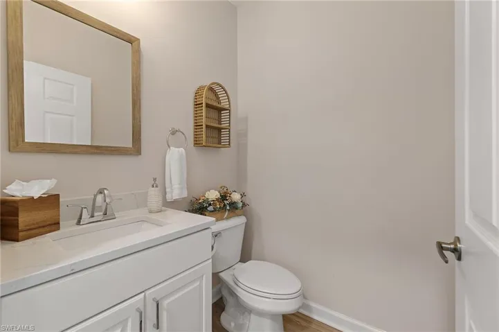 Bathroom featuring toilet, vanity, baseboards, and wood finished floors