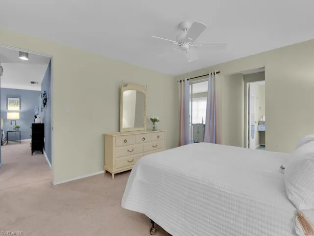 Carpeted bedroom featuring ensuite bathroom and ceiling fan