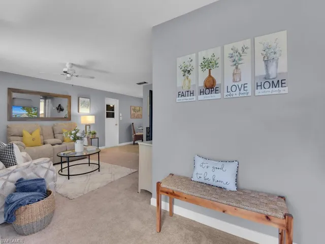 Living room with ceiling fan and light carpet