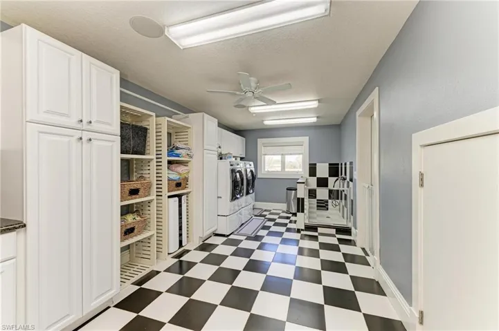 Laundry area featuring a textured ceiling, dark floors, a ceiling fan, cabinet space, and separate washer and dryer