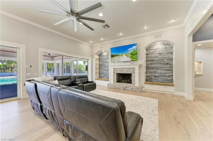 Living room featuring light wood-style flooring, visible vents, ornamental molding, and ceiling fan
