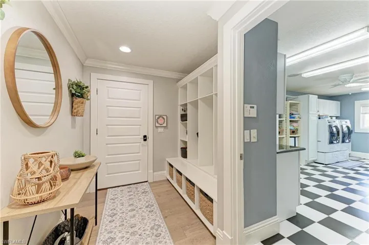 Mudroom featuring independent washer and dryer, baseboards, ornamental molding, a ceiling fan, and light floors