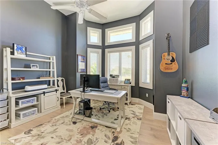 Home office featuring a ceiling fan, baseboards, and light wood-style floors