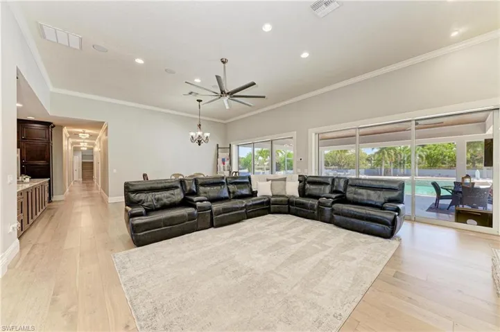 Living area with visible vents, ceiling fan with notable chandelier, and light wood finished floors