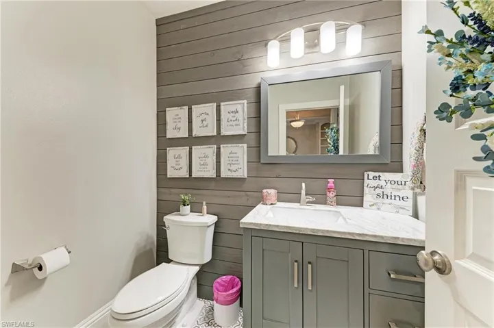 Bathroom with toilet, wood walls, and vanity