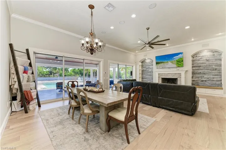 Dining area with ceiling fan with notable chandelier, visible vents, crown molding, and light wood-style flooring