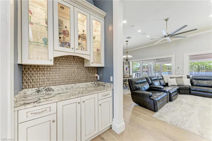 Kitchen with light wood-type flooring, open floor plan, decorative backsplash, and ornamental molding