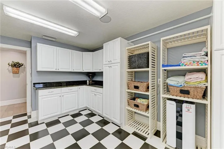 Kitchen with white cabinetry, visible vents, light floors, and a textured ceiling