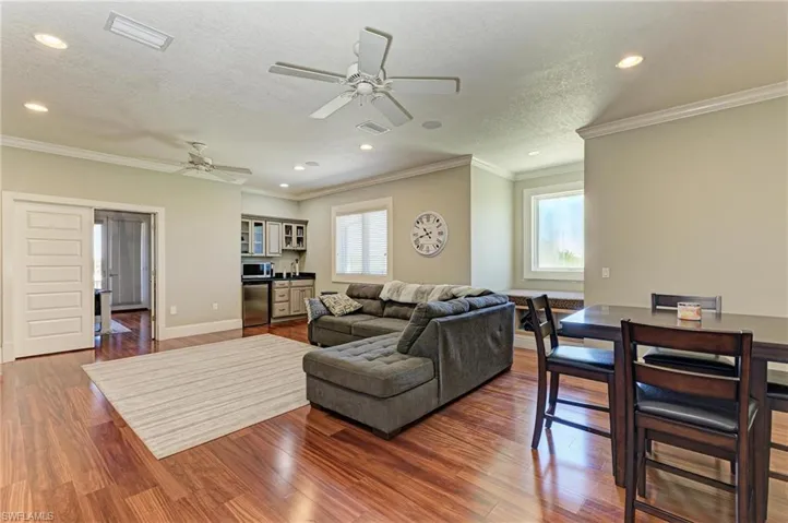 Living room with wood finished floors, visible vents, a healthy amount of sunlight, and ceiling fan