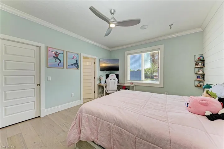 Bedroom with baseboards, wood finished floors, ceiling fan, and ornamental molding