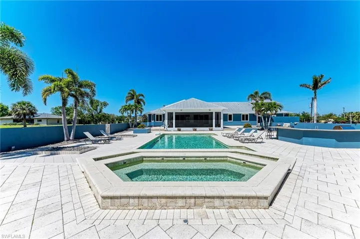 Community pool featuring a sunroom, fence, an in ground hot tub, and a patio area