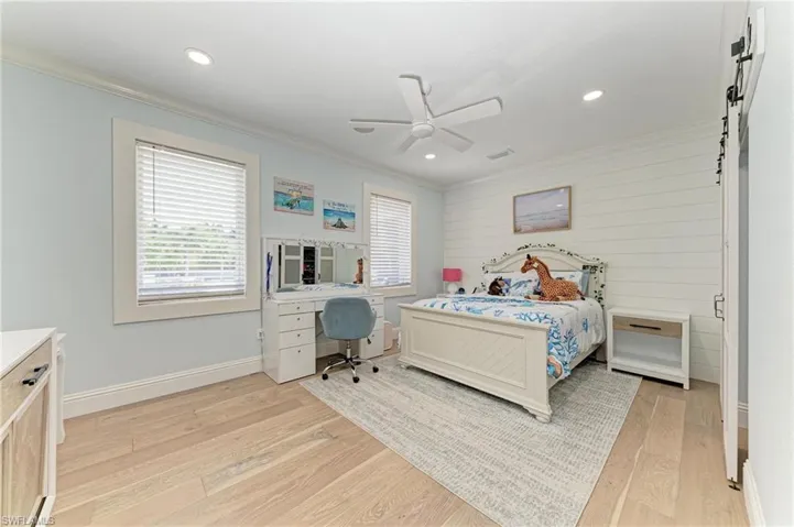 Bedroom with light wood finished floors, baseboards, crown molding, and recessed lighting
