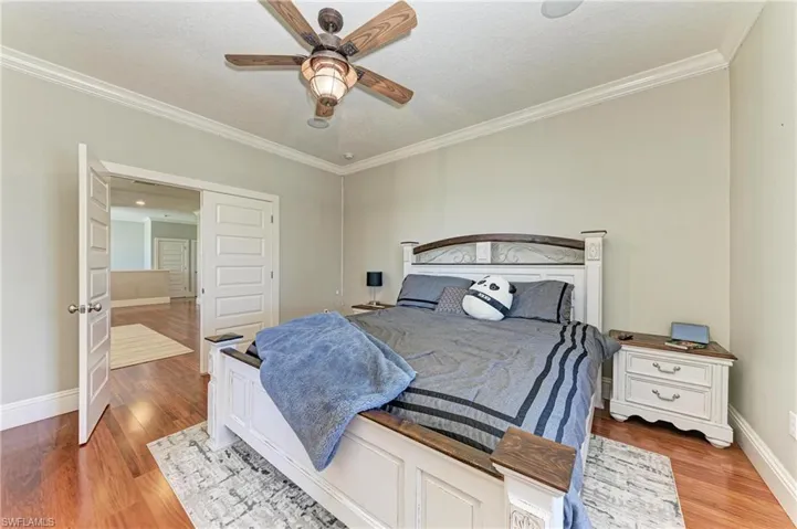 Bedroom with ornamental molding, baseboards, a textured ceiling, ceiling fan, and wood finished floors