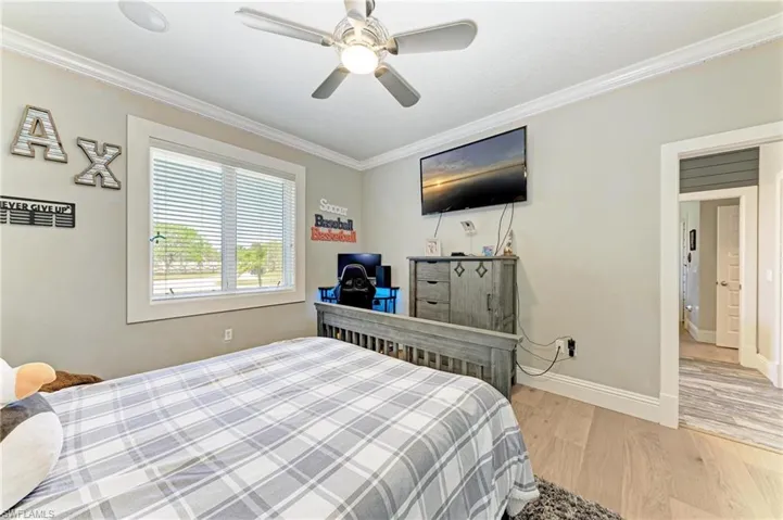Bedroom featuring light wood finished floors, baseboards, ceiling fan, and ornamental molding