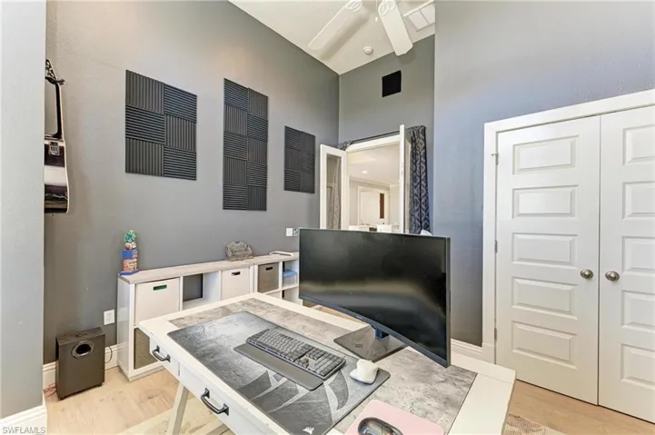 Home office with light wood-type flooring, baseboards, a high ceiling, visible vents, and ceiling fan