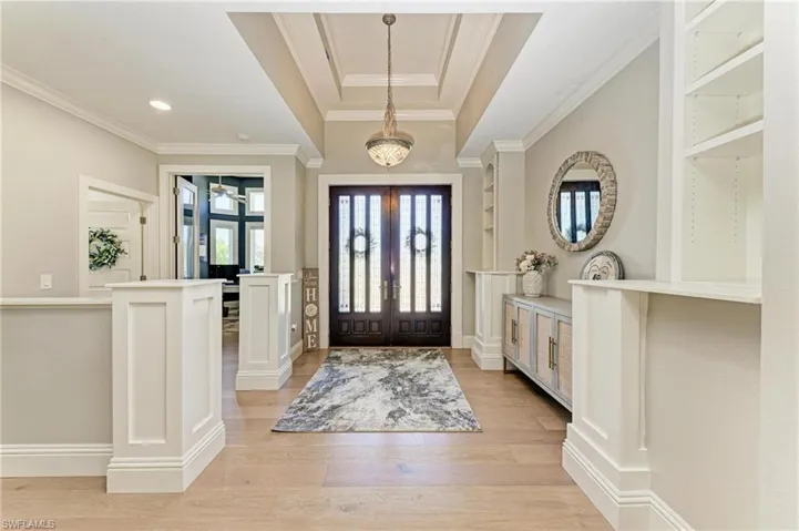 Foyer entrance featuring light wood-type flooring, ornamental molding, and french doors