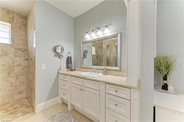 Bathroom featuring baseboards, a tile shower, tile patterned flooring, and vanity