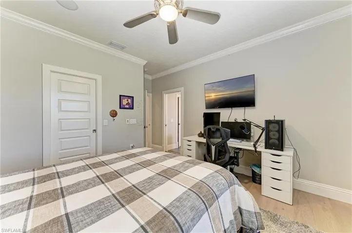 Bedroom featuring crown molding, a ceiling fan, baseboards, visible vents, and light wood-style floors