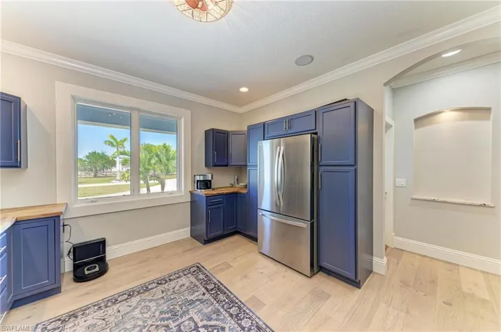 Kitchen with wooden counters, arched walkways, light wood-style flooring, and freestanding refrigerator