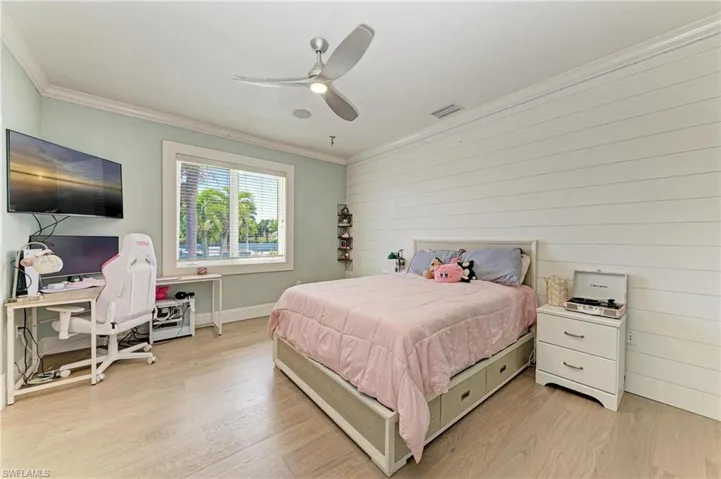 Bedroom featuring light wood-type flooring, a ceiling fan, crown molding, and visible vents