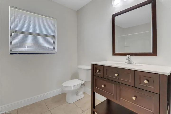 Bathroom with toilet, baseboards, tile patterned flooring, and vanity