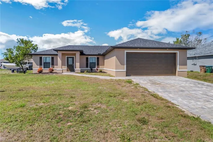 Prairie-style house with a front lawn, decorative driveway, a garage, and stucco siding