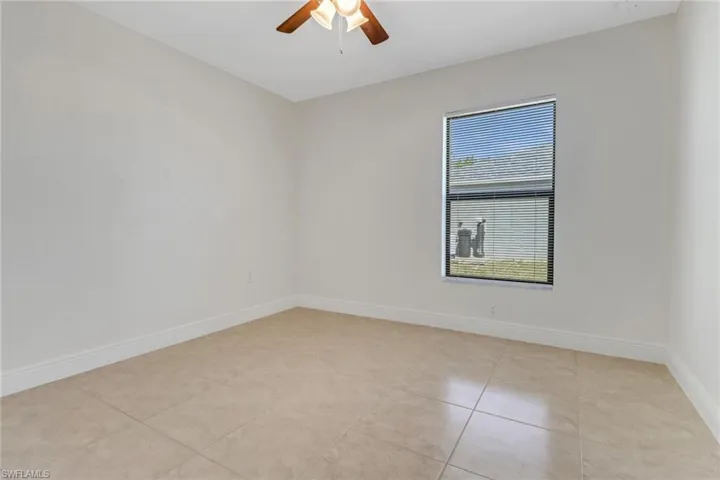 Spare room with light tile patterned floors, ceiling fan, and baseboards