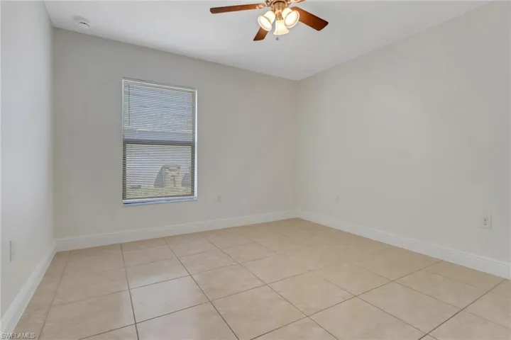 Spare room with light tile patterned floors, baseboards, and a ceiling fan