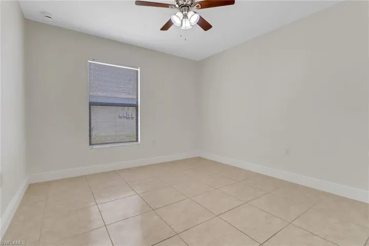 Unfurnished room with light tile patterned floors, ceiling fan, and baseboards