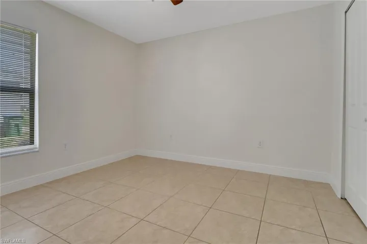 Spare room with light tile patterned flooring, baseboards, and a ceiling fan