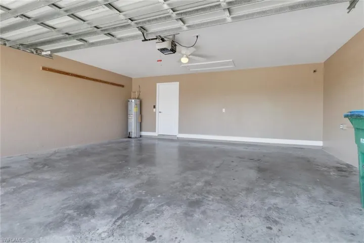 Garage with a garage door opener, concrete block wall, and water heater
