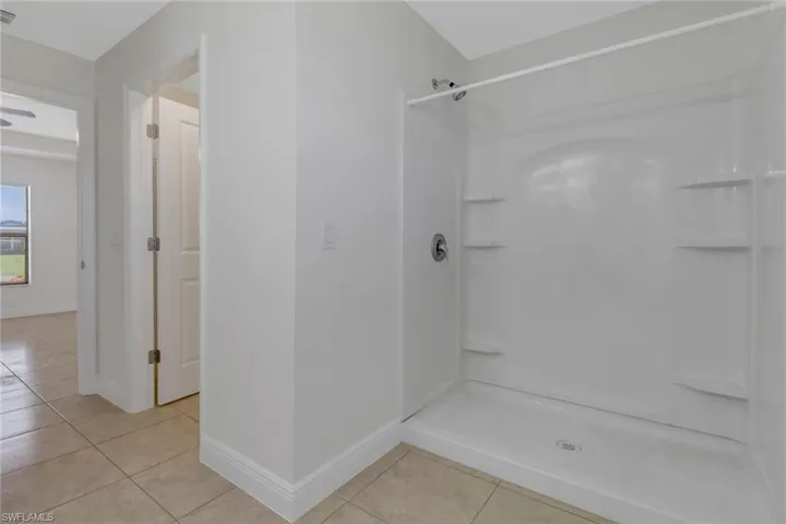 Bathroom with a shower, tile patterned floors, and baseboards