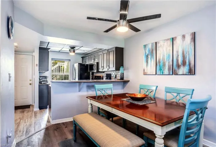 Dining area featuring wood-finish flooring, a contemporary ceiling fan, and a pass-through opening to the kitchen