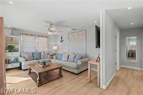Living room with a ceiling fan, light wood-style flooring, and recessed lighting