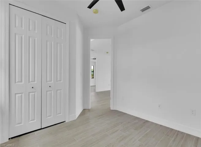 Unfurnished bedroom with ceiling fan, light hardwood / wood-style flooring, and a closet