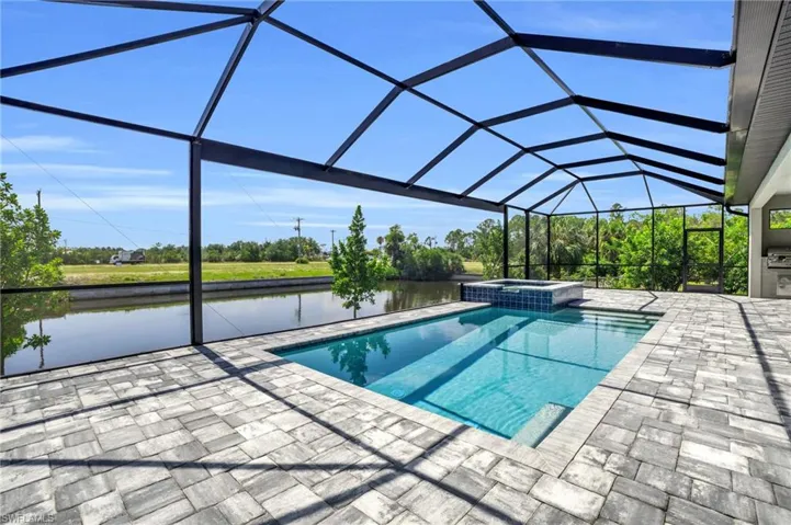 View of pool with a patio, an in ground hot tub, a water view, and glass enclosure