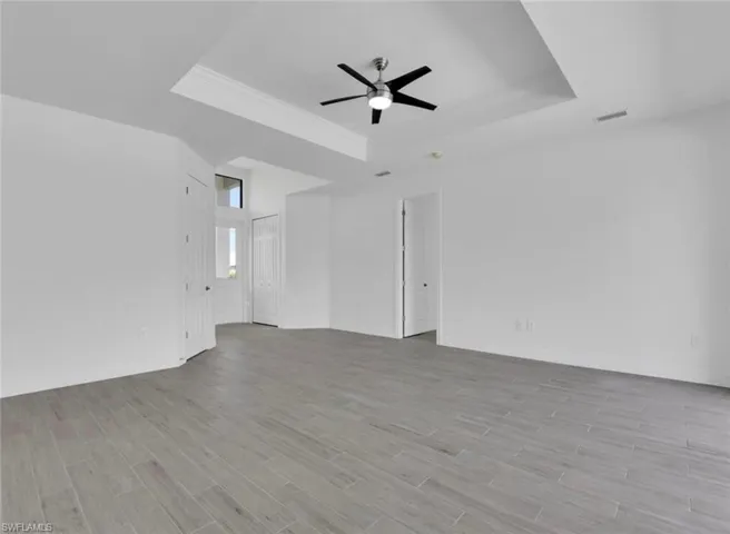 Spare room with ceiling fan, a raised ceiling, and light hardwood / wood-style flooring