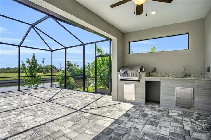 View of patio / terrace featuring ceiling fan, sink, a grill, an outdoor kitchen, and a lanai