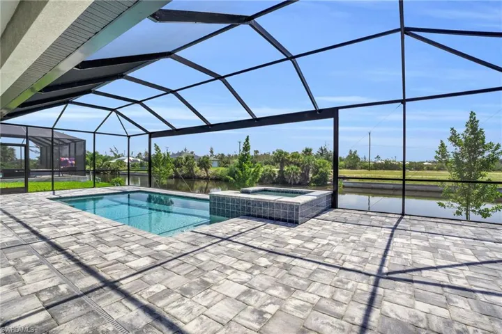 View of swimming pool featuring a water view, an in ground hot tub, a patio, and glass enclosure