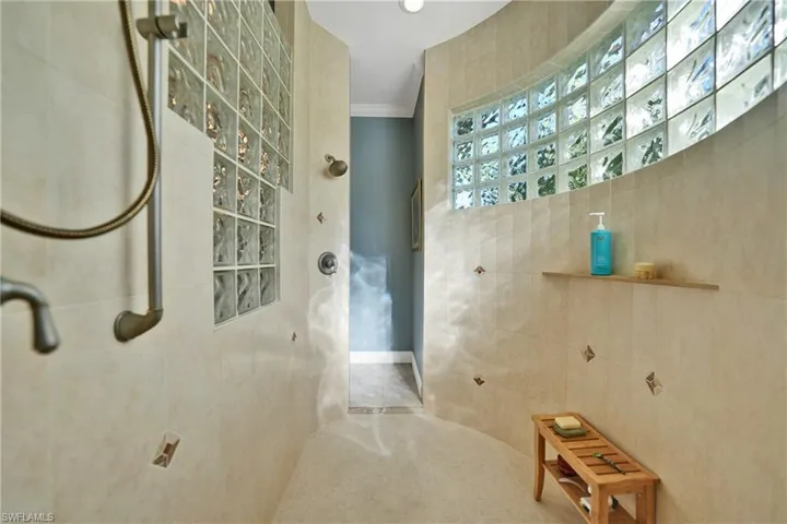 Bathroom featuring crown molding, walk in shower, and tile walls
