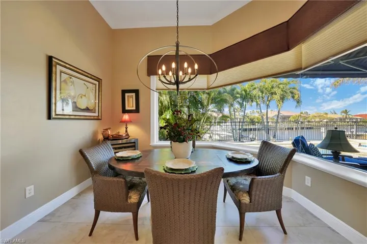 Dining room featuring ornamental molding, a water view, light tile patterned flooring, and a notable chandelier