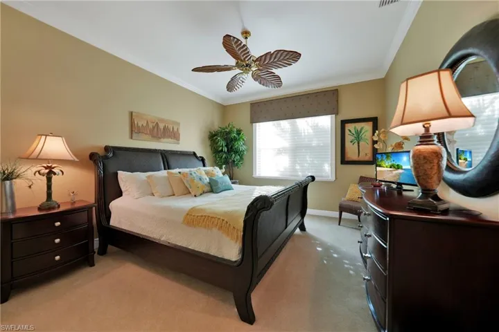 Carpeted bedroom featuring ceiling fan and ornamental molding