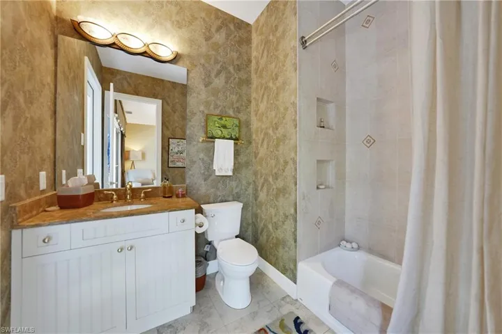 Full bathroom with shower / bath combo with shower curtain, vanity, and toilet