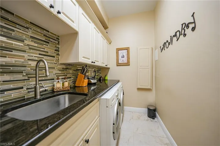 Washroom with washing machine and clothes dryer, sink, and cabinets