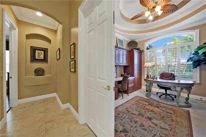 Office area featuring a raised ceiling, ceiling fan, and crown molding